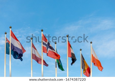 Flags of different countries on a flagpole against a blue sky. Natural photo.