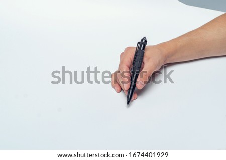 Male hand writes black pen on white paper