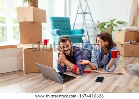 Beautiful young couple in love moving in together, surfing the net on laptop computer, searching the web for apartment redecoration ideas Royalty-Free Stock Photo #1674416626