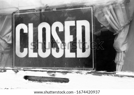 CLOSED sign in window of small business, black and white with hazy effect