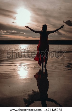 Girl sunset silhouette namaste red dress reflection in water 