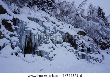 frozen ice falls and trees alongside the slope of the french ski resort of l'Alpe d'Huez
