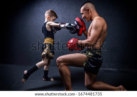 Kickboxing coach is training the boy. The concept of family, sports, mma, muay thai. Mixed media Royalty-Free Stock Photo #1674481735