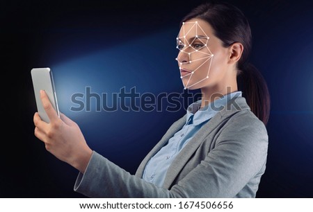 Facial recognition concept. Businesswoman with mobile phone using face scan system on black background