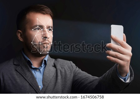 Unlocking smartphone with face recognition. Man with scanning mesh on face against black background