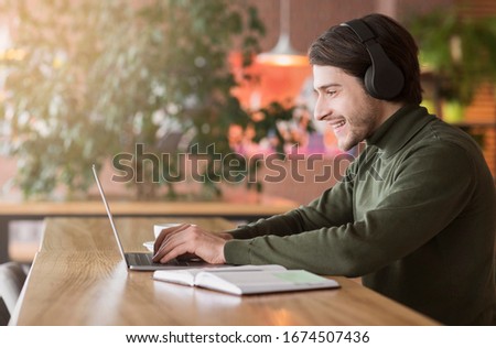 Modern businessman having skype conference on laptop, working at cafe, empty space Royalty-Free Stock Photo #1674507436