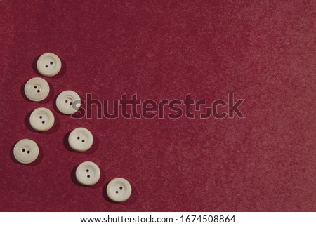 Lots of white buttons on a red textile background.