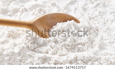 Background of potato starch flour powder texture close-up.Wooden spoon scoops potato starch. Royalty-Free Stock Photo #1674513757