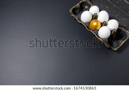 black egg stand with gold stands on a black background, in the stand are white and one golden egg, horizontal background, minimalism trend black monochrome