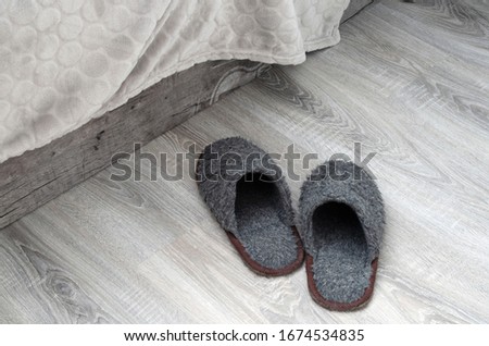 Gray faux fur Slippers next to the bed. A cozy home interior in shades of gray. Royalty-Free Stock Photo #1674534835