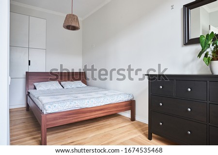 double wooden bed in a minimalistic white bedroom