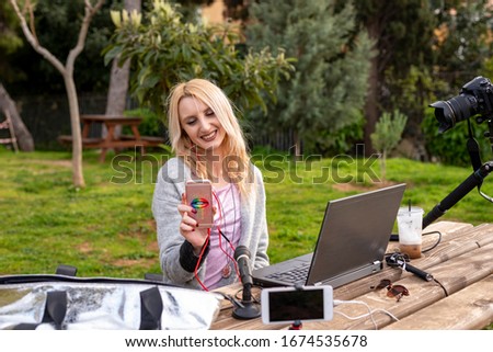 Female blond blogger interacting with her mobile - working outdoors - traveling the world - youtubers and influencers work concept