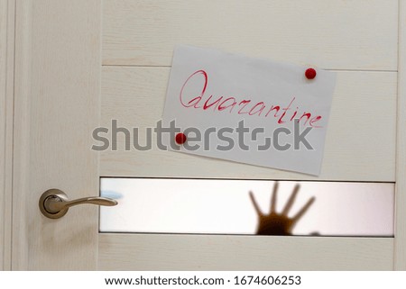 A red inscription Quarantine on the interior door, there are children's hands  shadows, silhouette  behind the door. Concept of coronavirus quarantine.