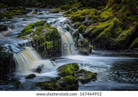 fantasy water rapid surrounded with stones covered with moss