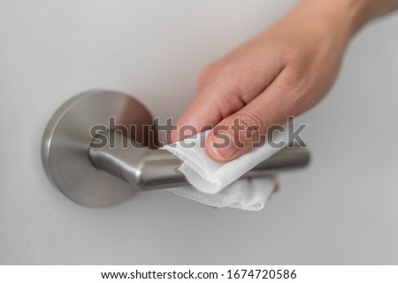 Coronavirus COVID-19 Prevention cleaning woman wiping doorknob with antibacterial disinfecting wipe for killing corona virus on touching surfaces or touching public bathroom handle with tissue. Royalty-Free Stock Photo #1674720586