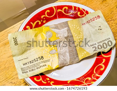 Two thousand rupiah bills, on a small plate