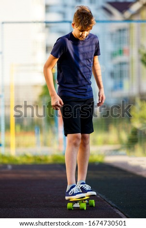 Cute cheerful smiling Boy in blue t shirt sneakers riding on yellow skateboard. Active urban lifestyle of youth, training, hobby, activity concept. Active outdoor sport for kids. Child skateboarding.