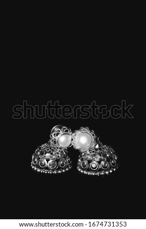Earring Gold Jewelry Traditional With Stones and Two Golden earrings with reflection . Pair of golden earring with pearl tone on black background. Luxury female jewelry, close-up