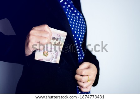 Close up hand of a businessman holding banknote into pocket.