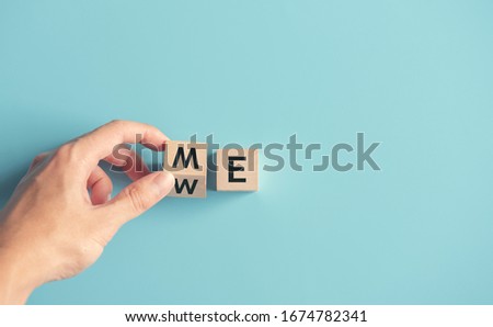 Hand flip wood cube with me or we on blue background, copy space. Royalty-Free Stock Photo #1674782341
