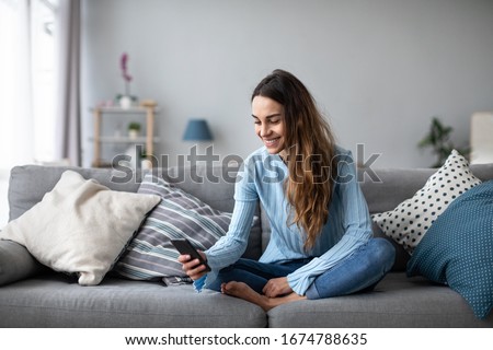 Smiling young woman at home using modern smartphone. Online chat. Royalty-Free Stock Photo #1674788635