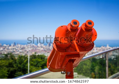 Red binoculars on the observation deck for tourists. Panoramic area with a red pair of binoculars with a view of the city Royalty-Free Stock Photo #1674862597