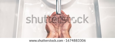 COVID-19 Coronavirus prevention washing hands with soap at bathroom sink man hand hygiene for corona virus pandemic precaution by washing hands frequently for 20 seconds. Panoramic banner. Royalty-Free Stock Photo #1674883306