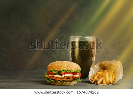 Street food or fast food. Hamburger, french fries and cola on table with wooden background. Unhealthy burger with beef.