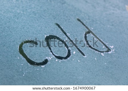 the word "cold" written with a finger on frozen glass