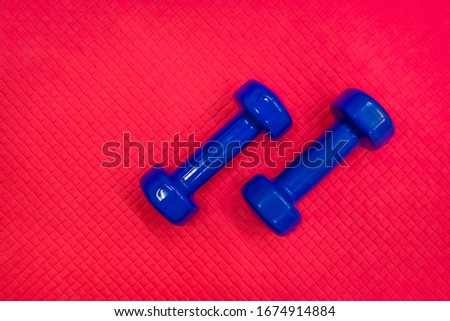 Blue dumbbells on the red floor of the gym