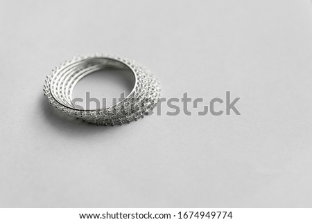 Silver bangles, white metal bangles on white background with plenty of copy space. Circular shapes, patterns, texture
