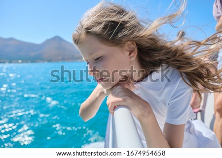 Beautiful little girl child blond enjoying sea voyage, sunny summer day, picturesque landscapes on horizon, copy space. Boat trip on small ship on Greek bay of Mirabello