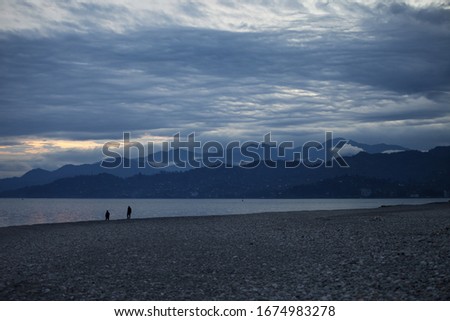 Pebbly beach, sea, silhouette of mountains and cloudy sky at evening. Black Sea coast, Georgia, Batumi.