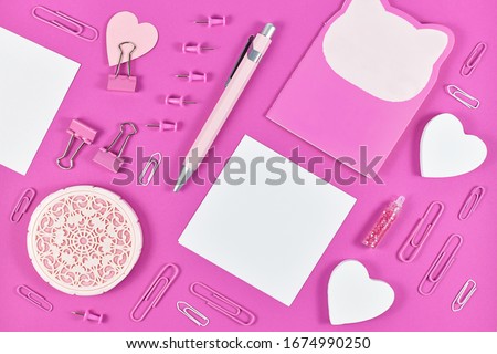 Flat lay with various pink arranged stationery office supplies like pen, note book, blank note paper, pins or retaining clip 