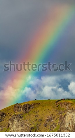 Rainbow over hill with horses and stone wall