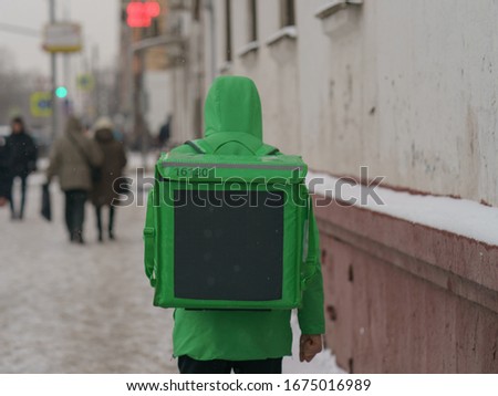 Photography of deliveryman on the street within winter day. Man going to the Client. Rear / back view.