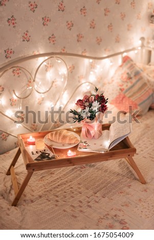 Morning breakfast in bed. Good morning.  Croissant with tea on the wooden table. Bouquet of flowers. Girl's room. Romantic breakfast. Wooden tray