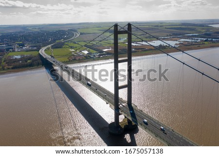 Aerial photo of The Humber Bridge, near Kingston upon Hull, East Riding of Yorkshire, England, single-span road suspension bridge, taken on a sunny day with a few white clouds in the sky. Royalty-Free Stock Photo #1675057138