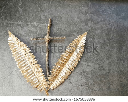 Christian cross with golden fern leaves on dark background. 