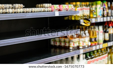 Empty egg shelves in a grocery store or supermarket. Hoarding food due to Coronavirus outbreak. Prepare food supplies for the worst case of COVID-19 pandemic. Stockpiling crisis all around the world.