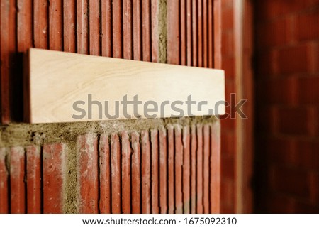 Blank wooden plaque on a brick wall, with free space to include text, a sign for free use information, with defocused background.
