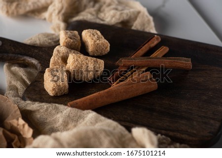 fresh cinnamon sticks and brown sugar on wooden cutting board near cloth