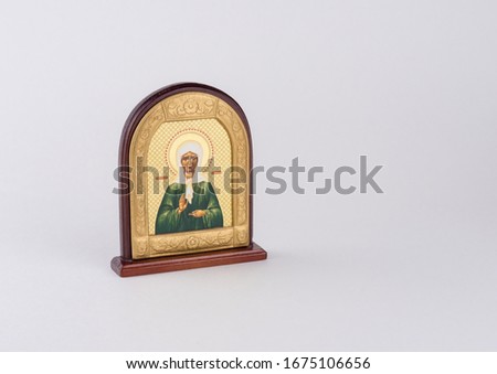 Small golden orthodox icon on a wooden stand, on a white background.