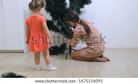 happy mom and daughter collect christmas tree at home. Christmas and New Year preparation.