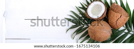 Coconut. Whole coconut, shell and green leaves on a white wooden background. Big nut. Tropical fruit coconut in the shell. SPA. Food photo. Photo background. Texture tropical fruit. Copy spase.