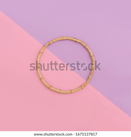 Round wooden frame, gymnastic hoop with wood texture over pink and lilac background