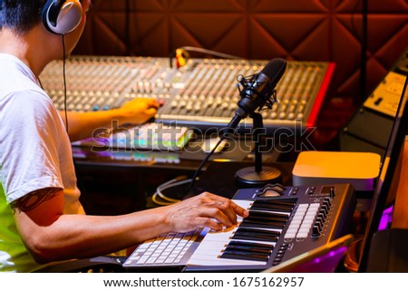 asian artist composing a song on computer and professional audio recording equipment in home studio