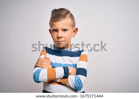 Young little caucasian kid with blue eyes standing wearing striped shirt over isolated background skeptic and nervous, disapproving expression on face with crossed arms. Negative person.