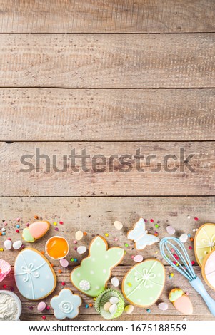 Easter cooking baking background with pastel colored easter cookies, sugar sprinkles and ingredients for bake cake and cookies.  Wooden rustic background, flatlay banner copy space