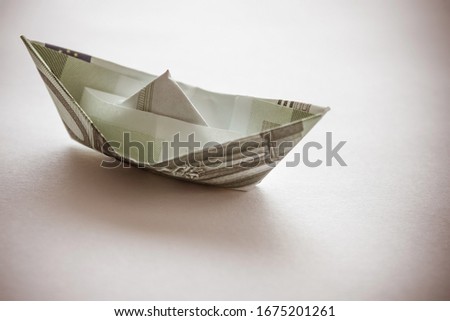The figurine of the ship is made of banknote. The cost of shipping, passenger transportation. Muted tones, vignetting.